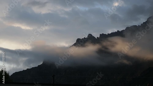 Dramatic landscape of rugged rocky mountain peaks shrouded in thick white fog and dense clouds. Majestic alpine scenery at high altitude with misty summits under an overcast sky — ideal for travel, ad