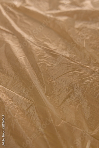 Bild auf Leinwand Close view of wrinkled brown plastic sheet on a flat surface in indoor light