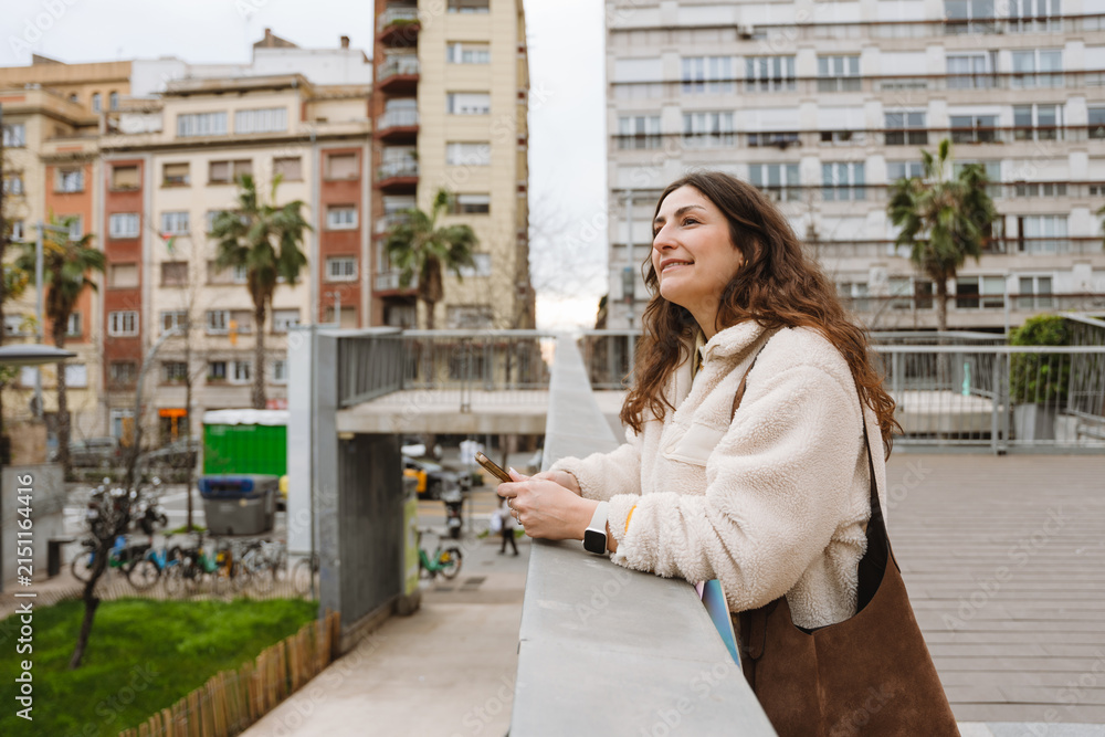 Fototapeta premium Woman holding a smartphone outdoors in the city