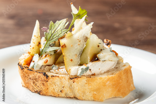 Photography Gourmet crostini with blue cheese, sliced pear, walnuts, and fresh herbs on toas