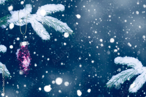 New Year background. Winter forest covered in snow. Glass Christmas pine cone on a tree. Snow covered spruce branch.