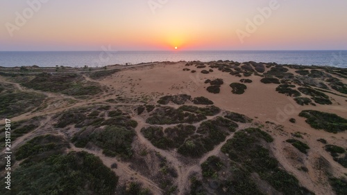 Aerial sunset over sandy coastal dunes and sea
