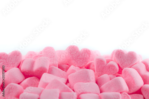 Pile of pink heart shaped marshmallows on a white background.
