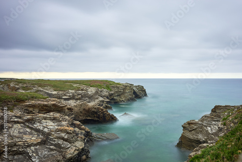 Moody long exposure of misty sea and rock at Praia das Catedrais, Beach of the Cathedrals in Ribadeo, Galicia Spain