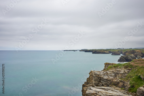 Moody long exposure of misty sea and rock at Praia das Catedrais, Beach of the Cathedrals in Ribadeo, Galicia Spain