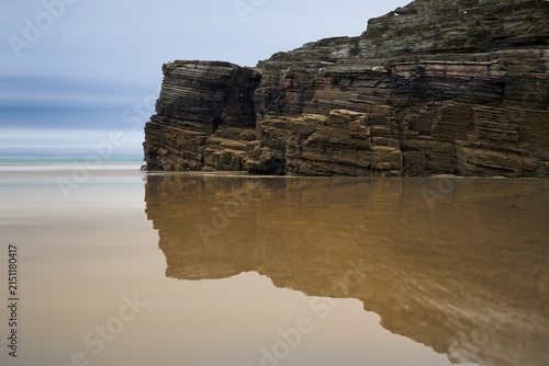 Moody long exposure of misty sea and rock at Praia das Catedrais, Beach of the Cathedrals in Ribadeo, Galicia Spain