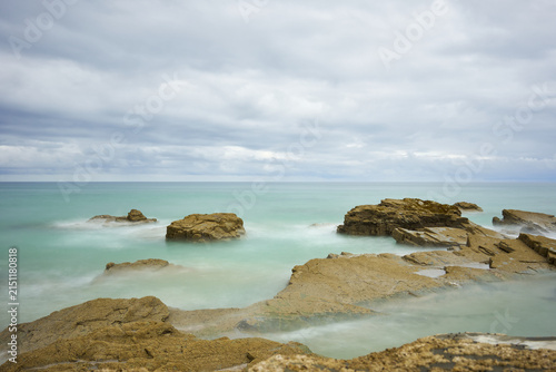 Moody long exposure of misty sea and rock at Praia das Catedrais, Beach of the Cathedrals in Ribadeo, Galicia Spain