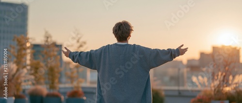 Silhouette of young adult standing at golden hour sunset