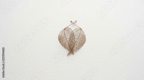 Delicate dry leaves forming a heart shape against a textured white surface
