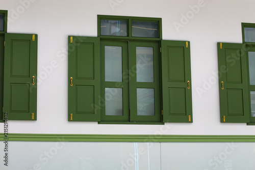 Cuadro en lienzo Classic green shutters with gold hardware adorn a white building facade