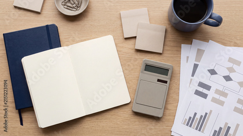 Flatlay of notebook, documents, and coffee cup with charts, business planning and analysis workspace concept