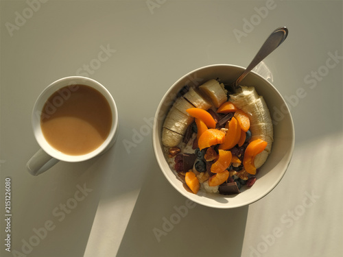 A healthy breakfast with fresh fruit, granola and yoghurt, enjoyed in the morning sunshine. Coffee with milk.