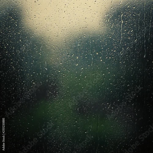 Raindrops running down window glass on stormy rainy day