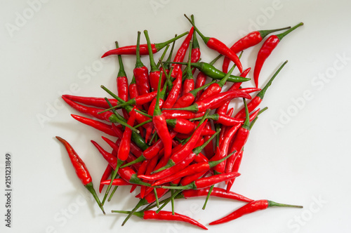 Obraz na płótnie Fresh red chili peppers piled on a white background with two green peppers creating natural contrast