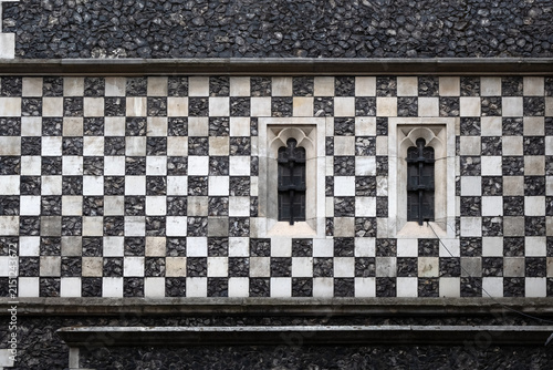 Chequerboard stone pattern on medieval church wall with small windows for use as a background texture