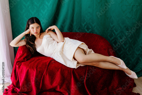 Elegant woman reclining on red velvet sofa