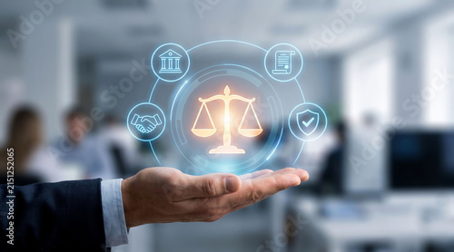 Business person holding a glowing digital interface showing legal scale icons and professional compliance symbols in a modern blurred office setting