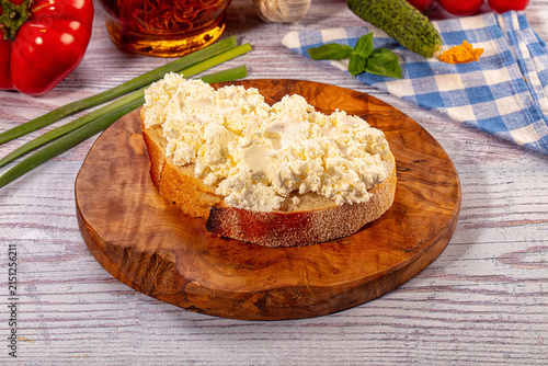 Cuadro en lienzo Toast with cottage cheese on wooden board surrounded by fresh vegetables and her