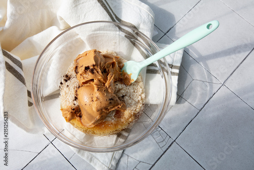Peanut butter, almond flour, natural vanilla seeds, and Jerusalem artichoke syrup in a glass bowl. Homemade cooking and healthy desserts concept. Handmade photograph, selective focus, hard sunlight