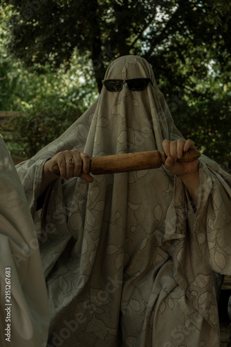 Person in Ghost Costume Holding Rolling Pin Outdoors