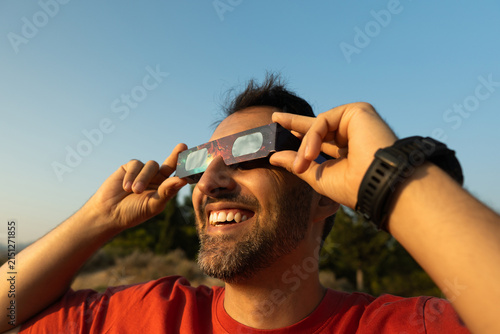 Man smiling enjoying solar eclipse with protective glasses