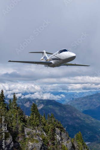 Private Business Jet Flying Above Mountain Clouds Over BC Canada Scenic Landscape
