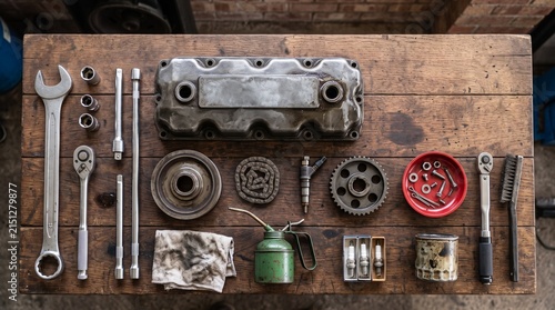 Mechanic's Workbench: A collection of tools and engine parts are neatly arranged on a wooden workbench, showcasing the raw materials of automotive repair and maintenance.