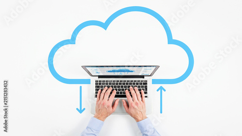 Top Down View of Person Typing on Laptop with Blue Cloud Outline Symbolizing Cloud Computing and Data Transfer