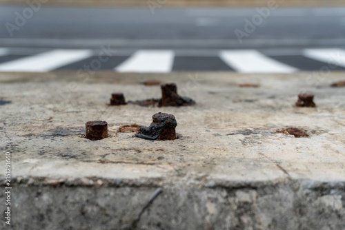 Quadro su tela Rusty bolts embedded in concrete near pedestrian crossing