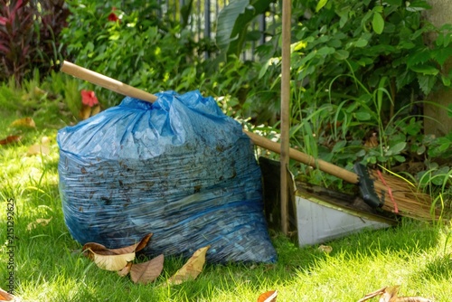 Blue bag filled with leaves in green garden