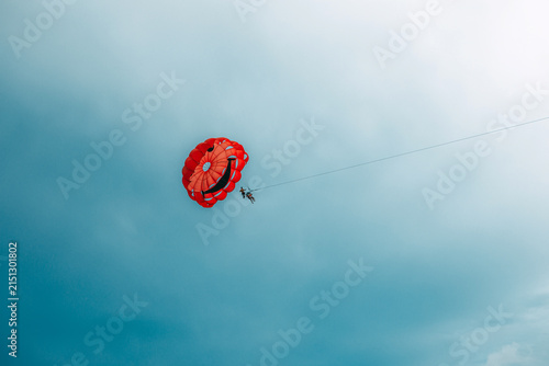 Red parachute parasailing activity in the bright blue sky