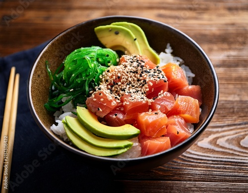 delicious tuna poke bowl with avocado seaweed and sesame seeds on a wooden table