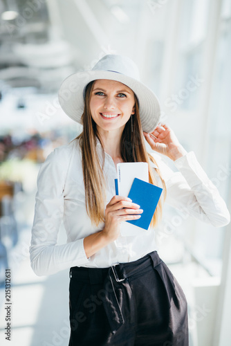 Young woman wearing hat and white shirt holding passport and ticket ready for travel