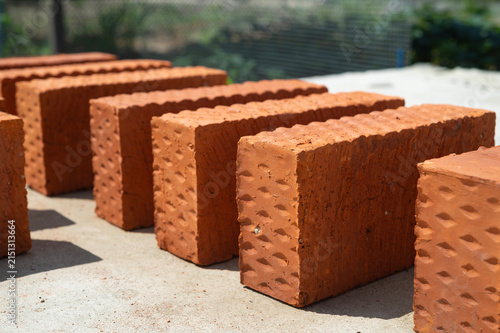 A row of red bricks lies on concrete for construction.