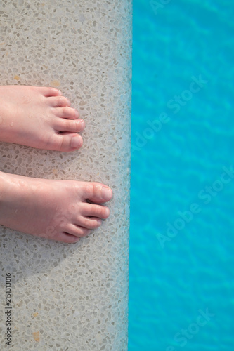 Children's feet at the edge of a swimming pool