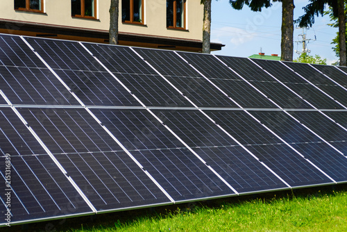 Solar panels installed on ground next to residential house generating clean green energy
