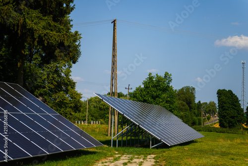 Ground mounted solar panels with wooden power pole against blue sky in countryside