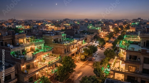 Aerial night view of illuminated city with green string lights and curving street