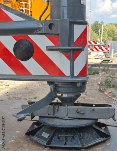 Фотография Close-up of a mobile crane hydraulic outrigger stabilizer leg with red and white hazard stripes on a construction site