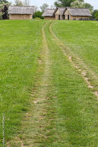 Dirt Track Through Green Meadow Leading to Thatched Cottages in Rural Countryside, Sopot culture, Vinkovci, Croatia