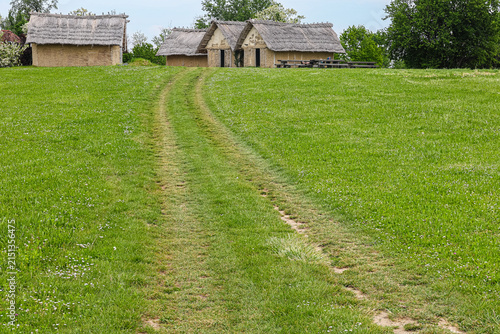 Dirt Track Through Green Meadow Leading to Thatched Cottages in Rural Countryside, Sopot culture, Vinkovci, Croatia