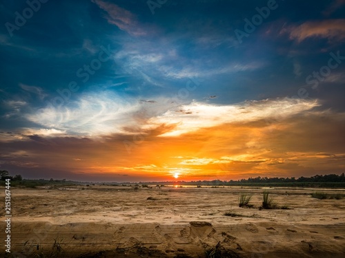 Fotografie A low autumn sun dips below the horizon, painting the crisp sky in fiery orange and soft violet