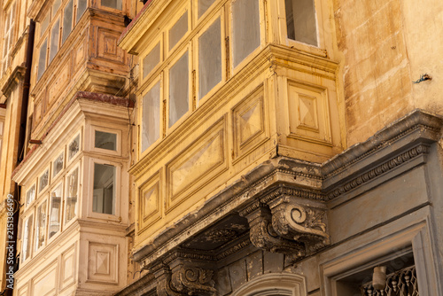 Fotografie Weathered wooden gallarija balconies in a traditional colour palette overhang a