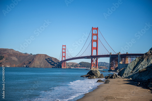 Golden Gate Bridge spans water with sandy beach in California during bright daylight