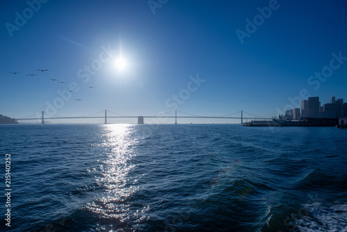 Sun shines over San Francisco Bay with Golden Gate Bridge and city skyline in view during the day