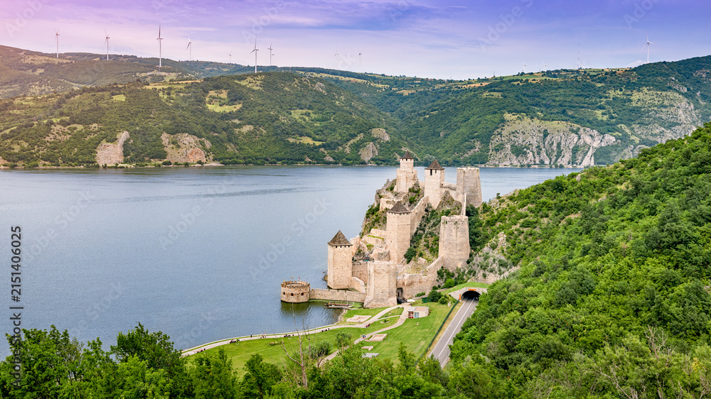 Fototapeta premium Medieval Golubac Fortress with its towers and walls along the Danube River, showcasing historic architecture and a tunnel road