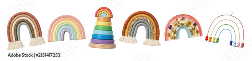 Collection of various rainbow-shaped toys and decor items including macrame hangings, a wooden stacker, a resin block with flowers, and a bead abacus for nursery or playroom