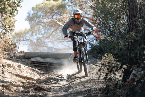 Mountain biker descending steep trail, kicking up swirling dust cloud