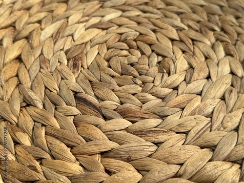 Close-up of decorative woven bamboo material with natural wood tones and intricate texture. Rustic organic surface ideal for interior, craft, nature, and background design concepts.