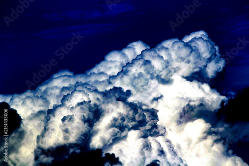 Obraz na płótnie A towering cumulonimbus cloud dominates the deep blue sky